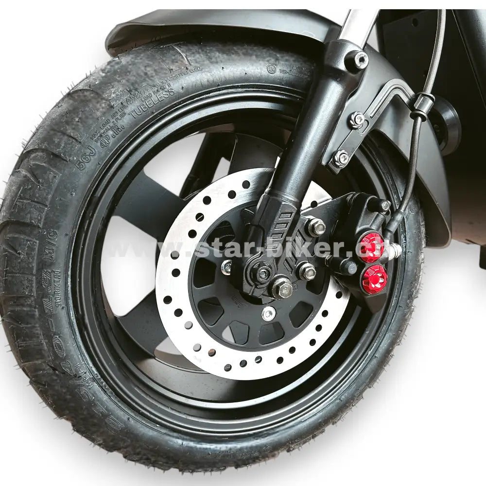 Vorderrad des Star-Biker Cruiser 3.0s mit gelochter Scheibenbremse, roter Bremszange und robustem Breitreifen. Detailansicht der Vorderradbremse.